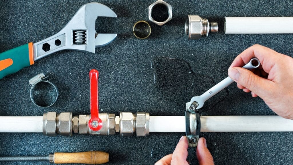 Plumber repairing a pipe valve with an adjustable wrench in Chula Vista