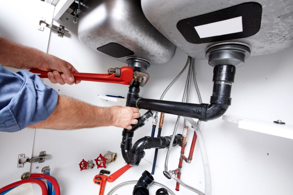 Plumber repairing drain pipes beneath a kitchen sink in Chula Vista