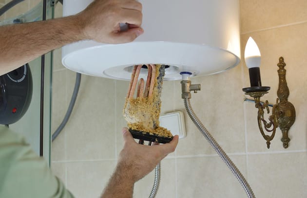 Technician removing mineral buildup from a water heater in Chula Vista