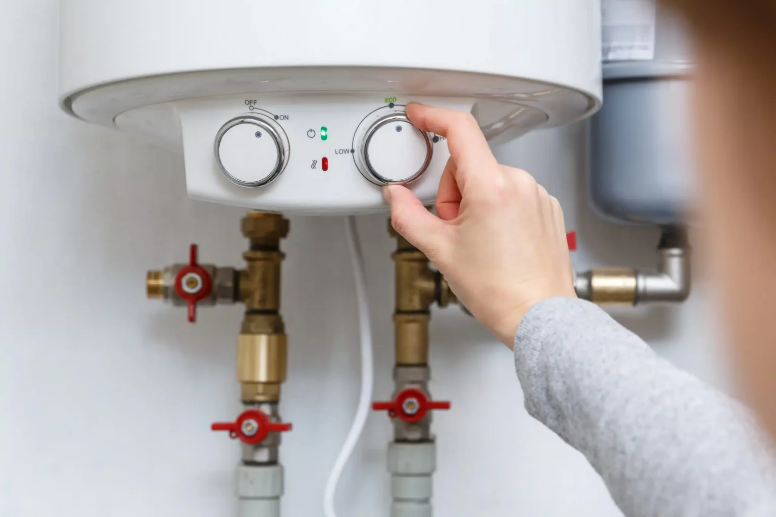 Homeowner adjusting the temperature controls on a water heater in Chula Vista